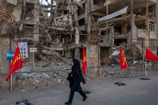 A woman walks past buildings destroyed in a joint attack by Israel and the US on April 6, 2026, in Tehran, Iran